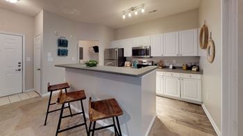 A kitchen with a large island with two stools in front of it